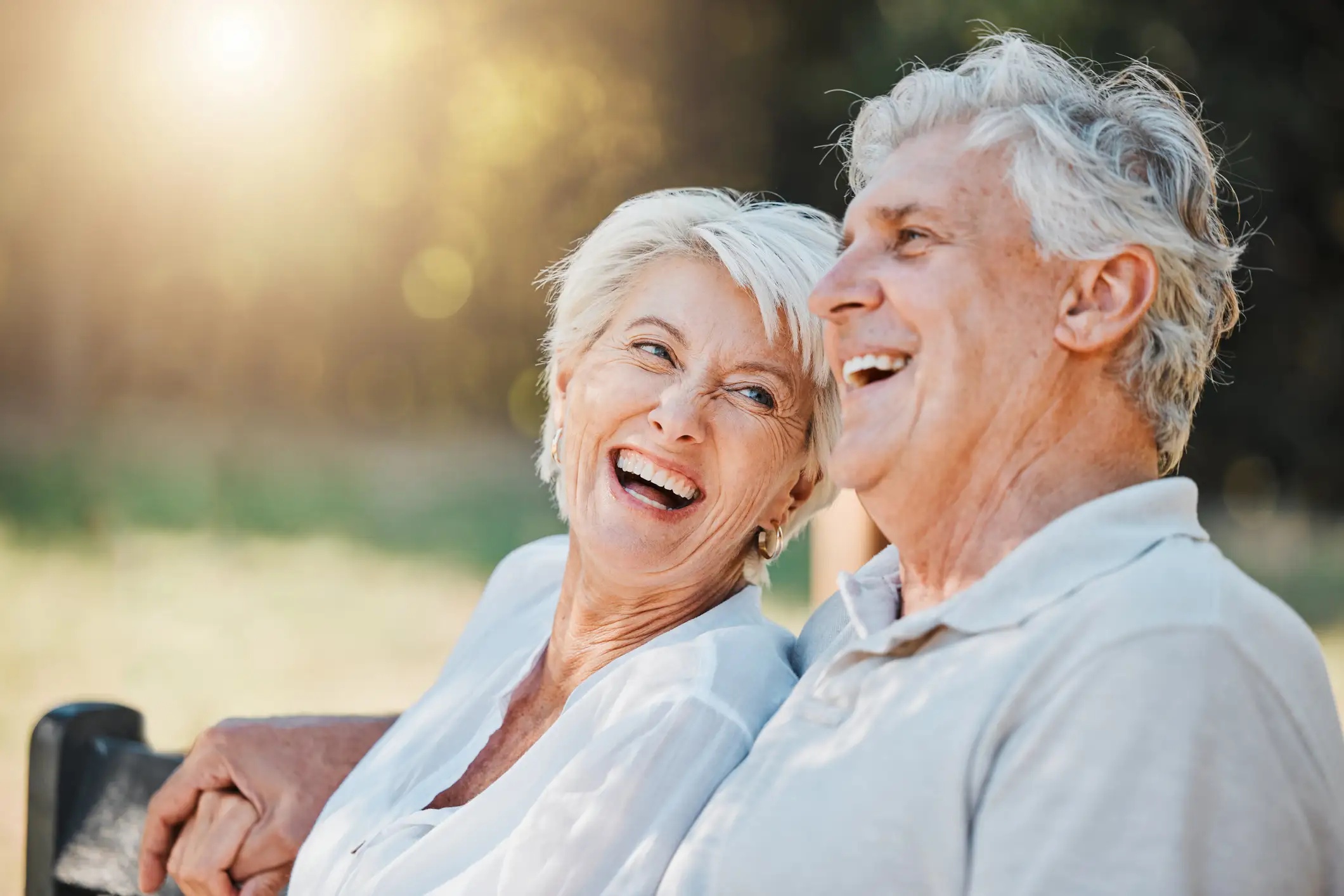 iStock-1767104100JuneBlogImage Senior couple outdoors on a park bench watching the sun rise and smiling